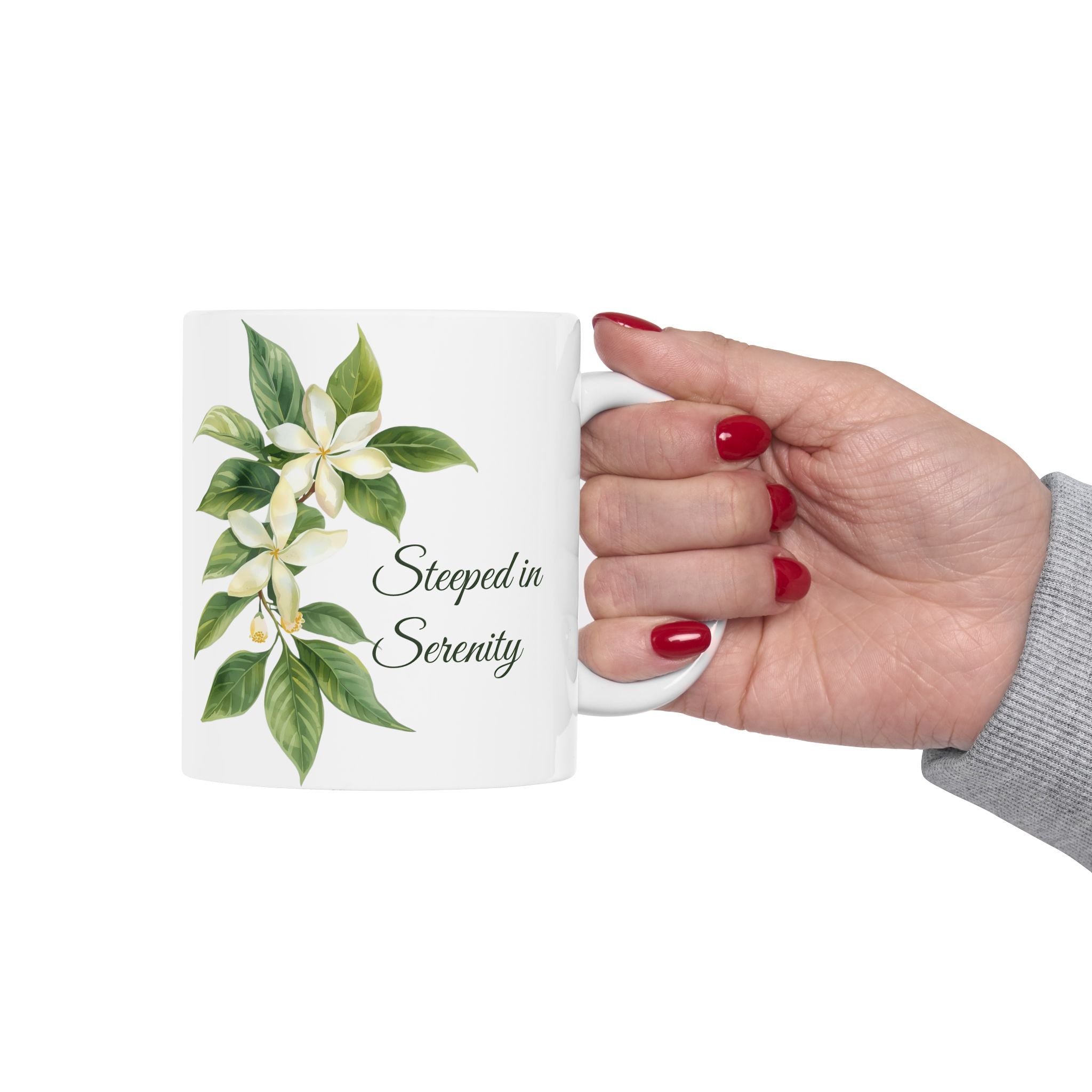 Hand holding a mug with floral design and text 'Steeped in Serenity' on a white background