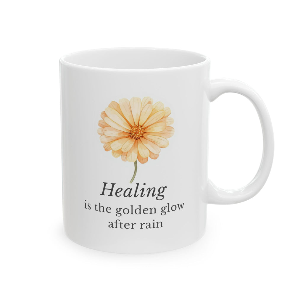 White ceramic mug with a calendula flower design and text 'Healing is the golden glow after rain' on a white background