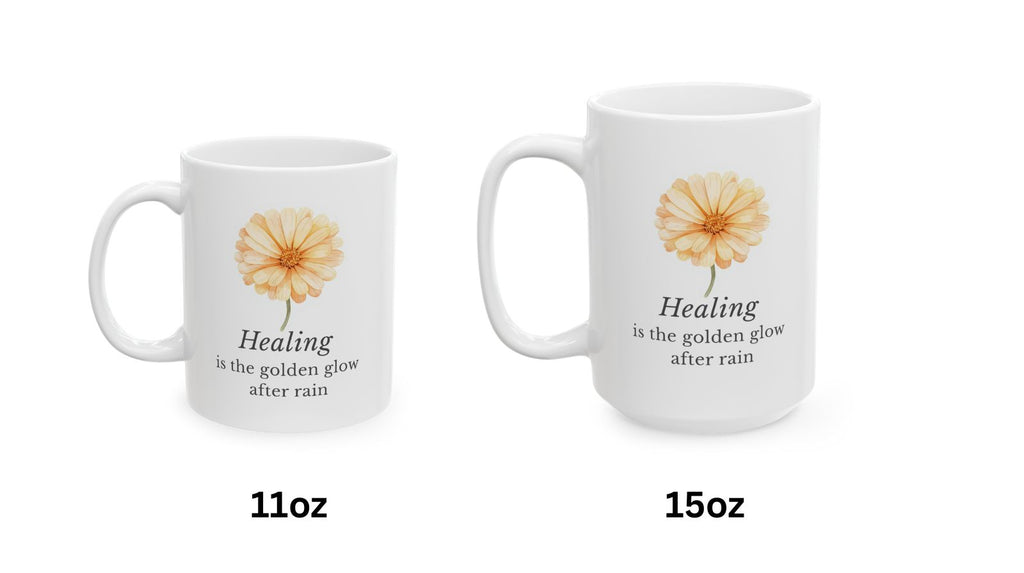 Two white mugs with calendula flower designs and text 'Healing is the golden glow after rain' on a white background