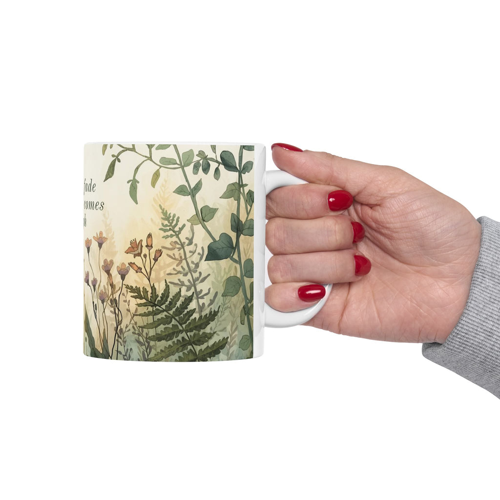 Hand holding a ceramic mug with a botanical design on a white background