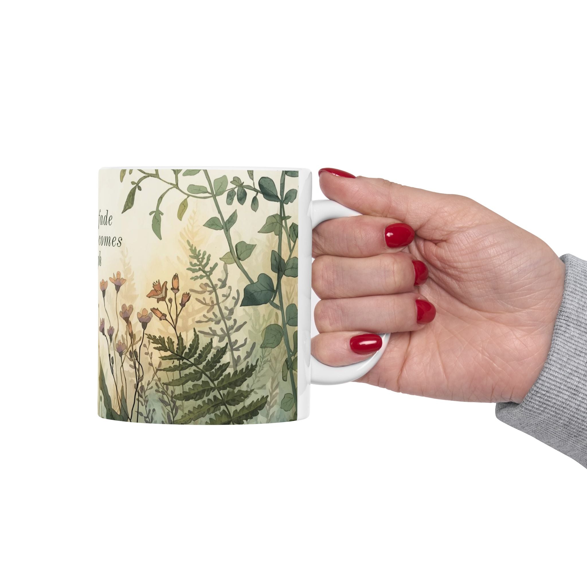 Hand holding a ceramic mug with a botanical design on a white background