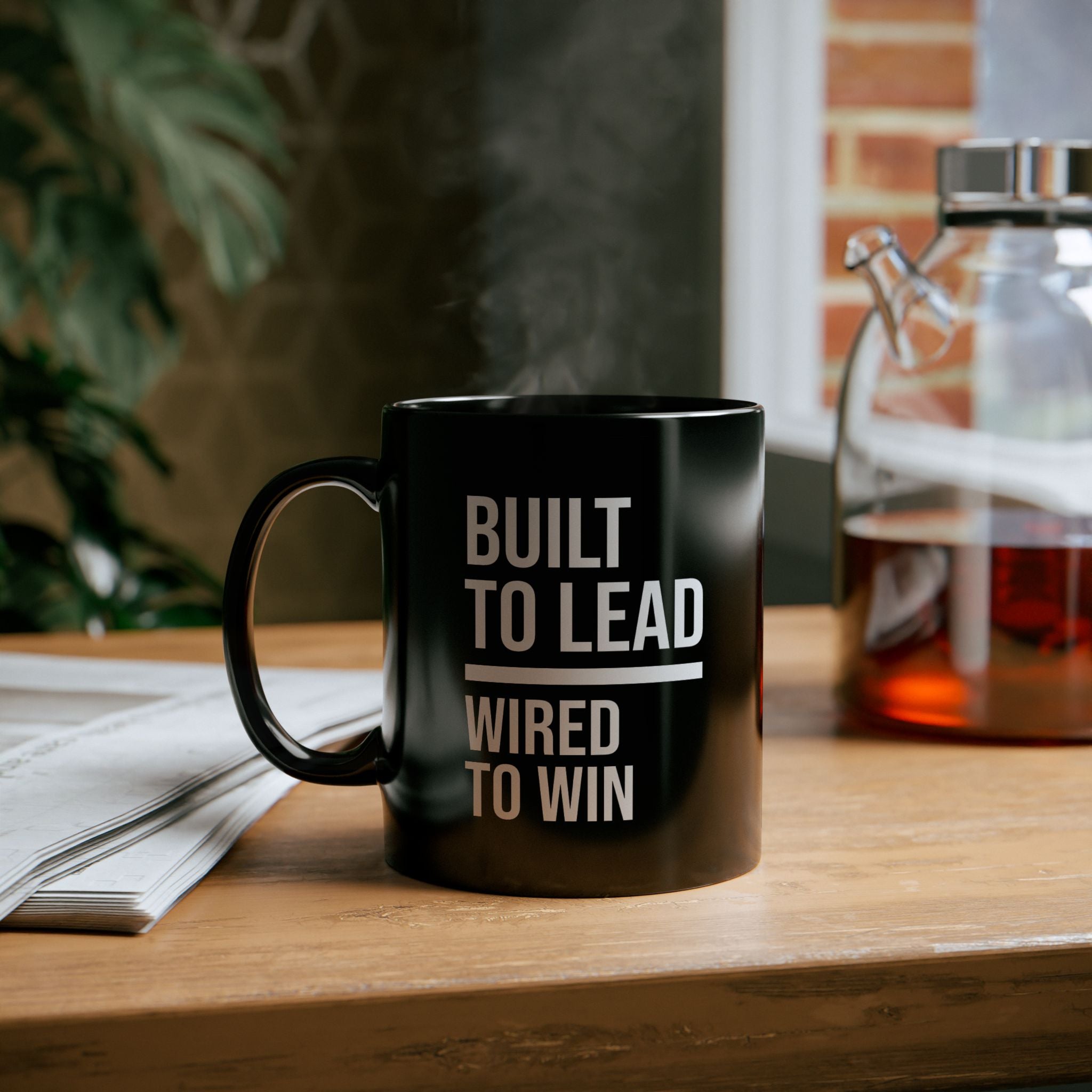 Black mug with 'Built to Lead, Wired to Win' text on a wooden table.